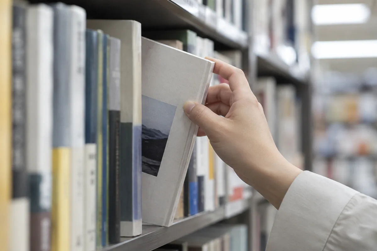 書店の棚から一冊の本を引き出す手