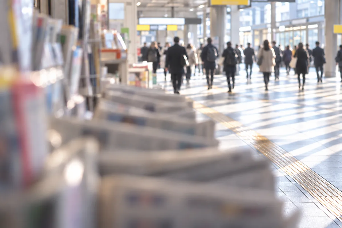 新聞の並ぶ売り場越しに見える朝の人通り