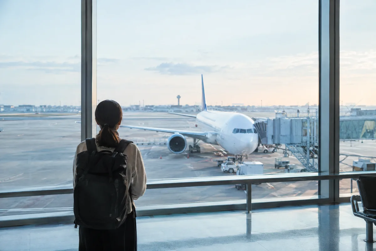 空港の窓から飛行機を見る人の後ろ姿