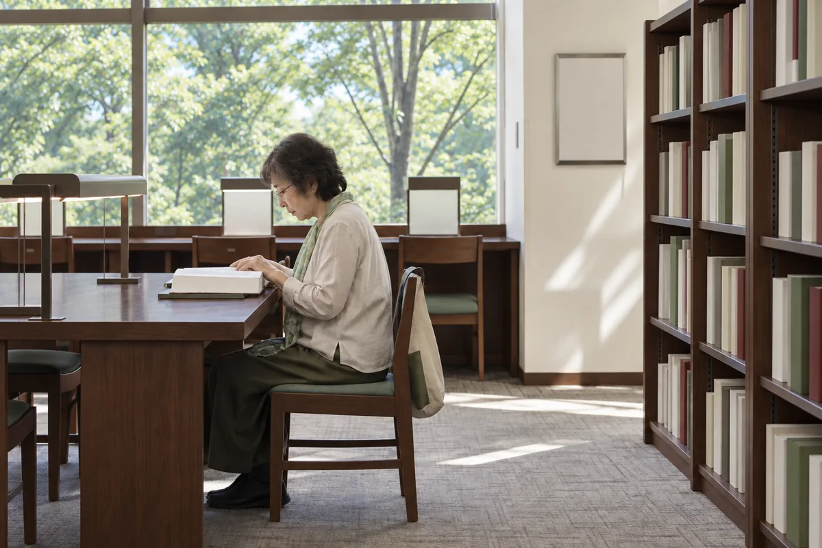 図書館で眼鏡をかけて厚い本を読む女性